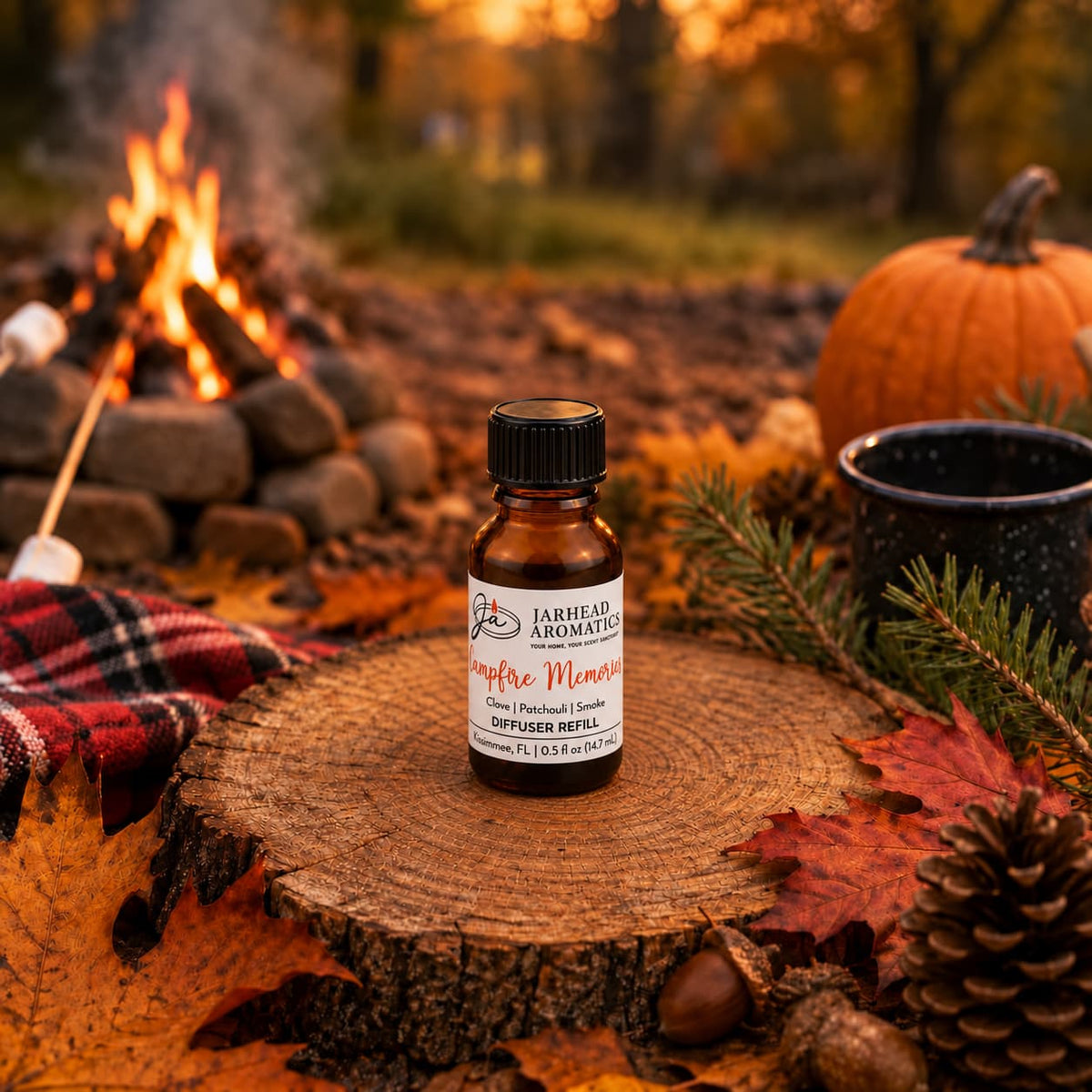 A bottle of Jarhead Aromatics Campfire Memories Cold Air Diffuser Refill | Maple, Clove & Smoky Embers rests on a tree stump surrounded by autumn leaves, pinecones, a mug, a pumpkin, and a plaid blanket, with a campfire glowing in the background among vibrant fall trees.