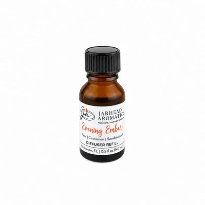 A small amber glass bottle with a black cap holds the Jarhead Aromatics Evening Ember Cold Air Diffuser Refill, featuring notes of plum, sandalwood, and soft smoke. This home fragrance oil offers a warm and inviting aroma, ideal for use as a cold air diffuser refill. The bottle contains 0.5 fl oz (14.7 ml).