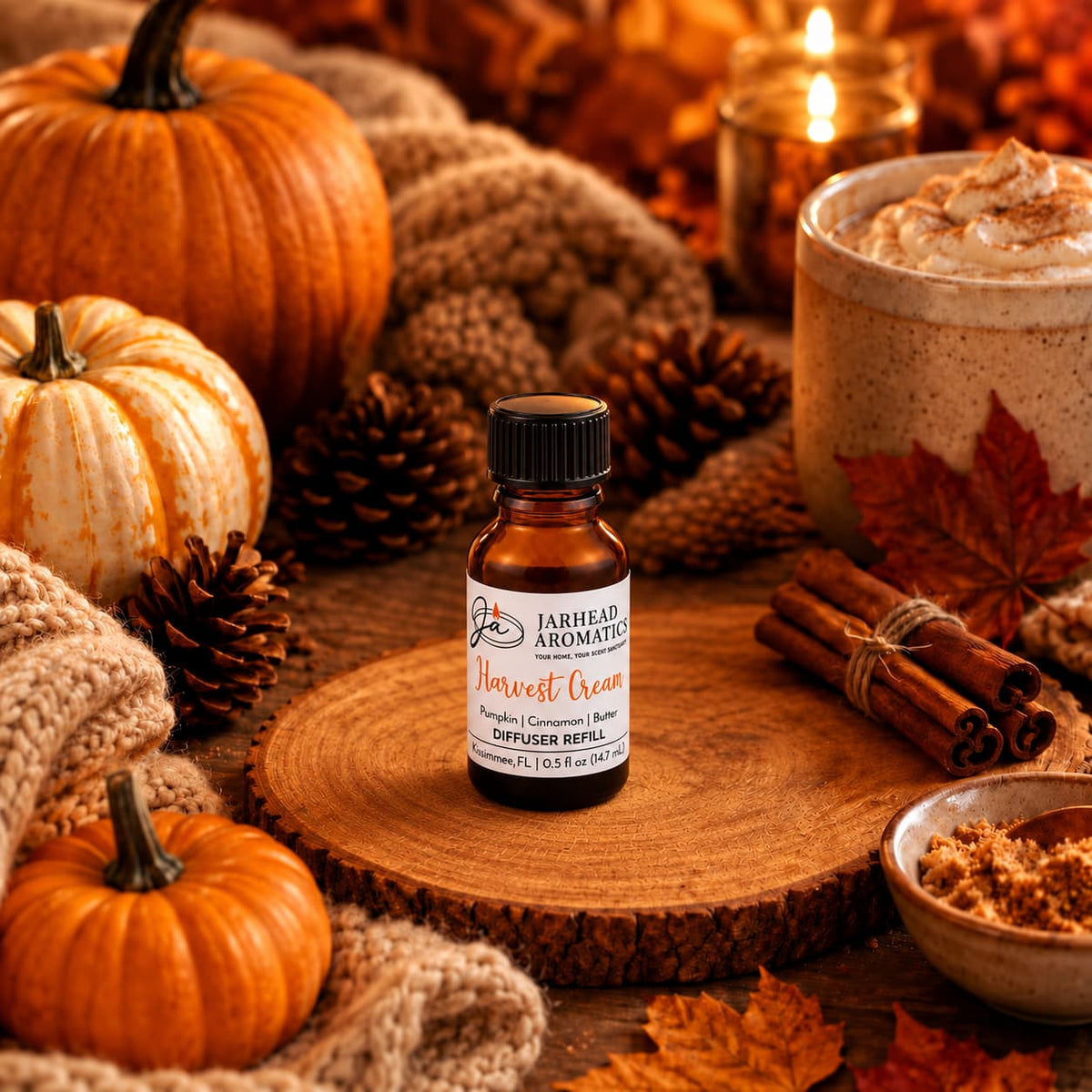 A small bottle of Jarhead Aromatics Harvest Cream Cold Air Diffuser Refill—featuring notes of pumpkin spice, brown sugar, and vanilla cream—rests on a wooden slab surrounded by pumpkins, pinecones, cinnamon sticks, cozy knits, and a creamy drink mug. Candlelight glows softly in the background, evoking a warm autumn atmosphere that’s perfect for your pumpkin spice diffuser or as a cold air diffuser refill.