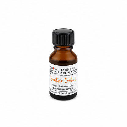 A small amber glass bottle of Santa’s Cookies Cold Air Diffuser Refill with a black cap and a white label, featuring a scent profile of ginger, molasses, and clove.