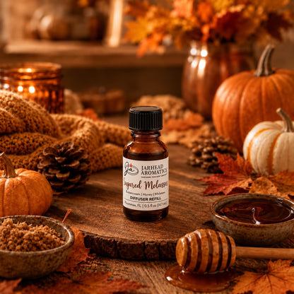 A bottle of Jarhead Aromatics Sugared Molasses Cold Air Diffuser Refill | Buttercream, Honey & Dark Molasses rests on a wooden table amid pumpkins, autumn leaves, a honey dipper, and cozy fall décor in warm lighting, infusing the space with an inviting gourmand fragrance that’s perfect for the season.