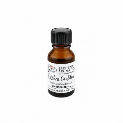 An amber glass bottle labeled “Witches Cauldron Cold Air Diffuser Refill | Orange Blossom, Patchouli & Dark Incense” by Jarhead Aromatics, featuring a Halloween-inspired fragrance blend, is displayed against a white background.
