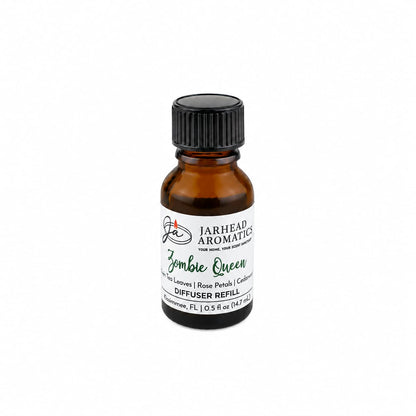 A small amber bottle labeled Jarhead Aromatics Zombie Queen Cold Air Diffuser Refill—blending black tea, rose petals, and cedarwood—rests on a white background with its black screw cap, infusing your home with an enchanting gothic aroma that adds a mysterious touch to any space.