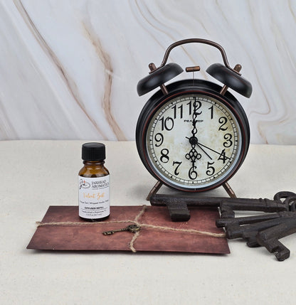 The Velvet Zest Cold Air Diffuser Refill by Jarhead Aromatics sits alongside two vintage metal keys, an old alarm clock, and a tied brown envelope on a light marble surface.