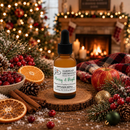 A brown Merry & Bright Car Diffuser Refill | Citrus Cranberry, Warm Spice & Fir bottle sits on a wooden slice surrounded by cranberries, cinnamon sticks, orange slices, and evergreen branches in front of a fireplace.