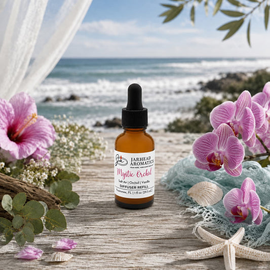 A bottle of Jarhead Aromatics Mystic Orchid Car Diffuser Refill—featuring notes of orchid, salt air, and vanilla—rests on a wooden surface surrounded by pink orchids, seashells, and greenery, with the ocean and blue sky behind it, capturing the refreshing essence of a coastal scent for your car.
