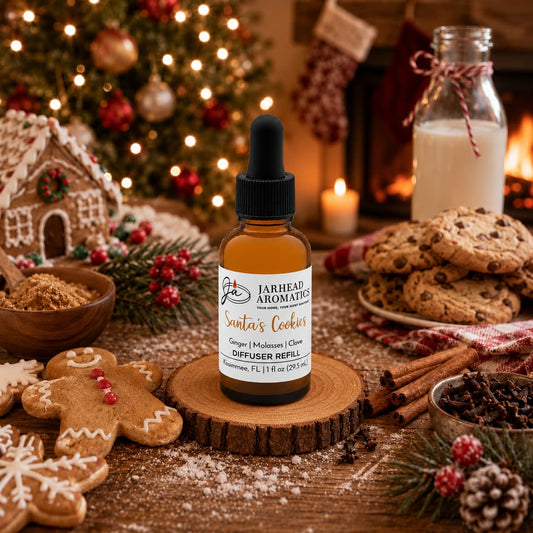 A bottle of Santa’s Cookies Car Diffuser Refill by Jarhead Aromatics sitting on a wood slice surrounded by gingerbread cookies, cinnamon sticks, and holiday decorations.
