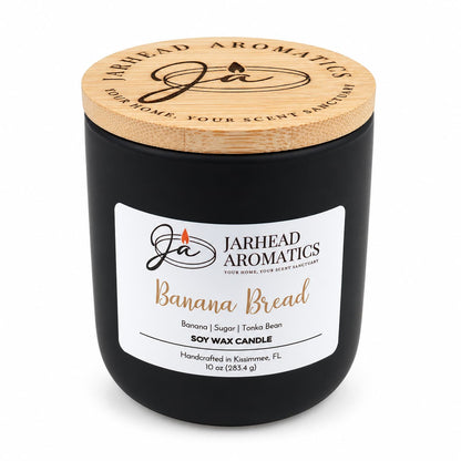 Banana Bread Soy Wax Candle | Banana, Sugar & Tonka Bean in a black glass jar with a wooden lid and a label featuring the scent notes.
