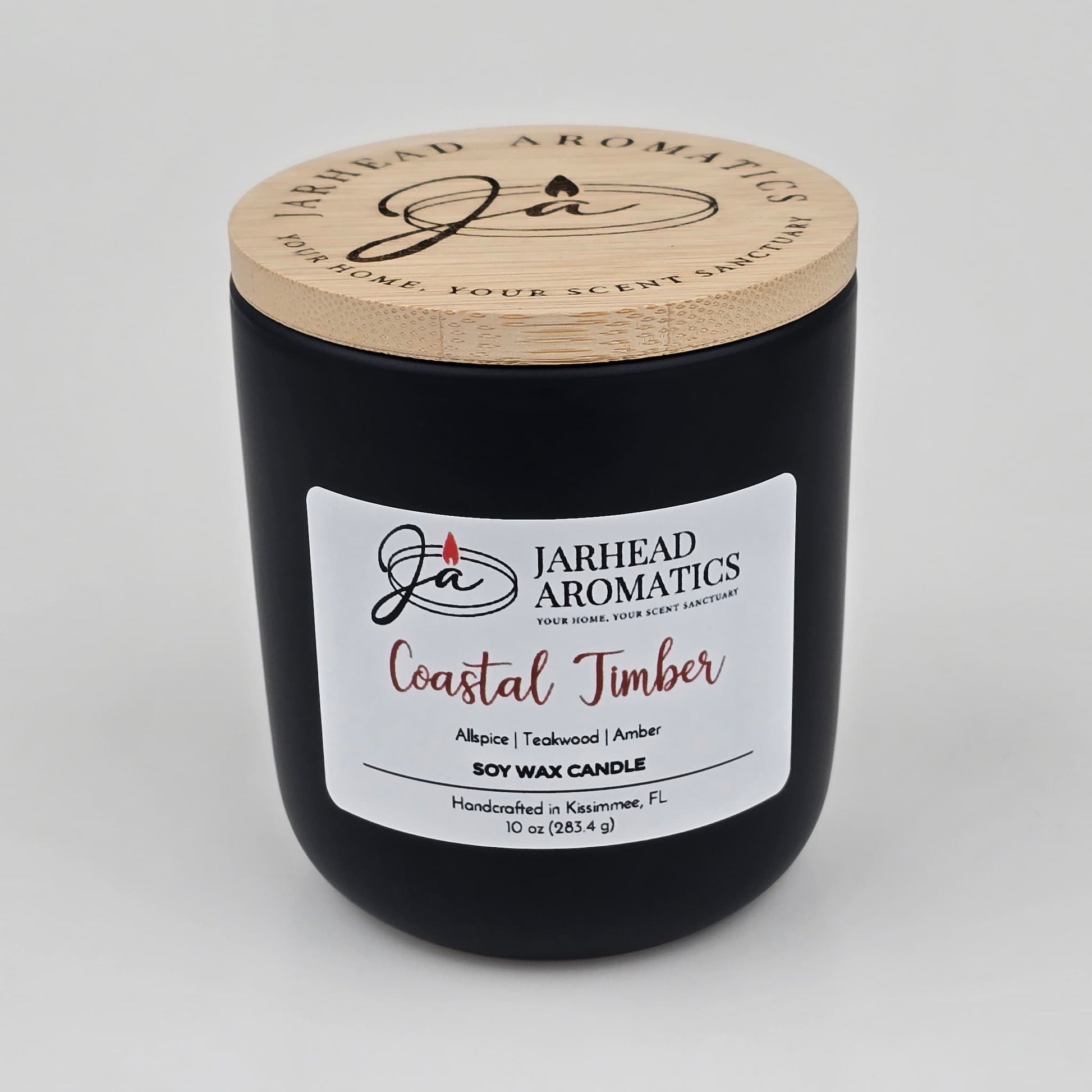 Jarhead Aromatics Coastal Timber Soy Wax Candle | Teakwood, Leather & Amber Candle comes in a sleek black jar with a wooden lid. This handcrafted soy candle, made in Kissimmee, FL, offers a woodsy and masculine fragrance profile featuring notes of teakwood, leather, and amber. Made from pure soy wax for a clean and long-lasting burn.
