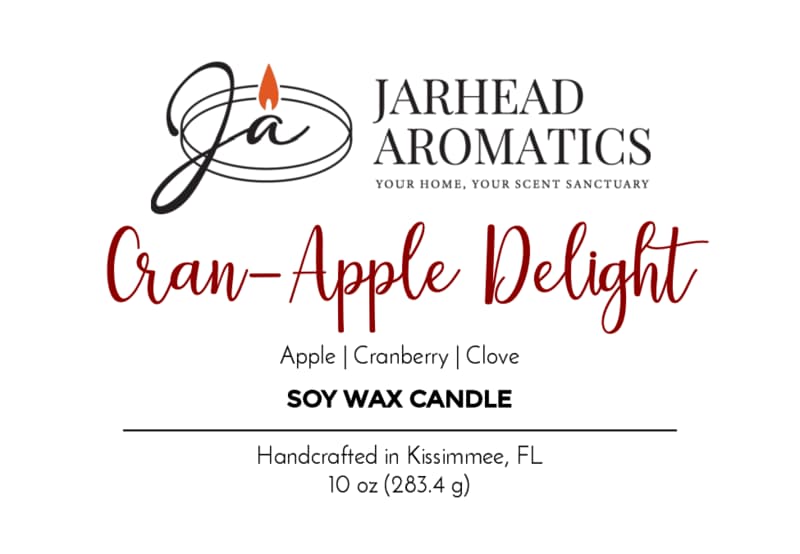Jarhead Aromatics label for Cran-Apple Delight Soy Wax Candle | Cranberry, Apple & Cinnamon Candle. Scent notes: cranberry, apple, and cinnamon. Handcrafted in Kissimmee, FL. White background with black and red text, featuring a candle flame logo. Enjoy the warm aroma of our Cran-Apple Delight Soy Wax Candle with every burn.