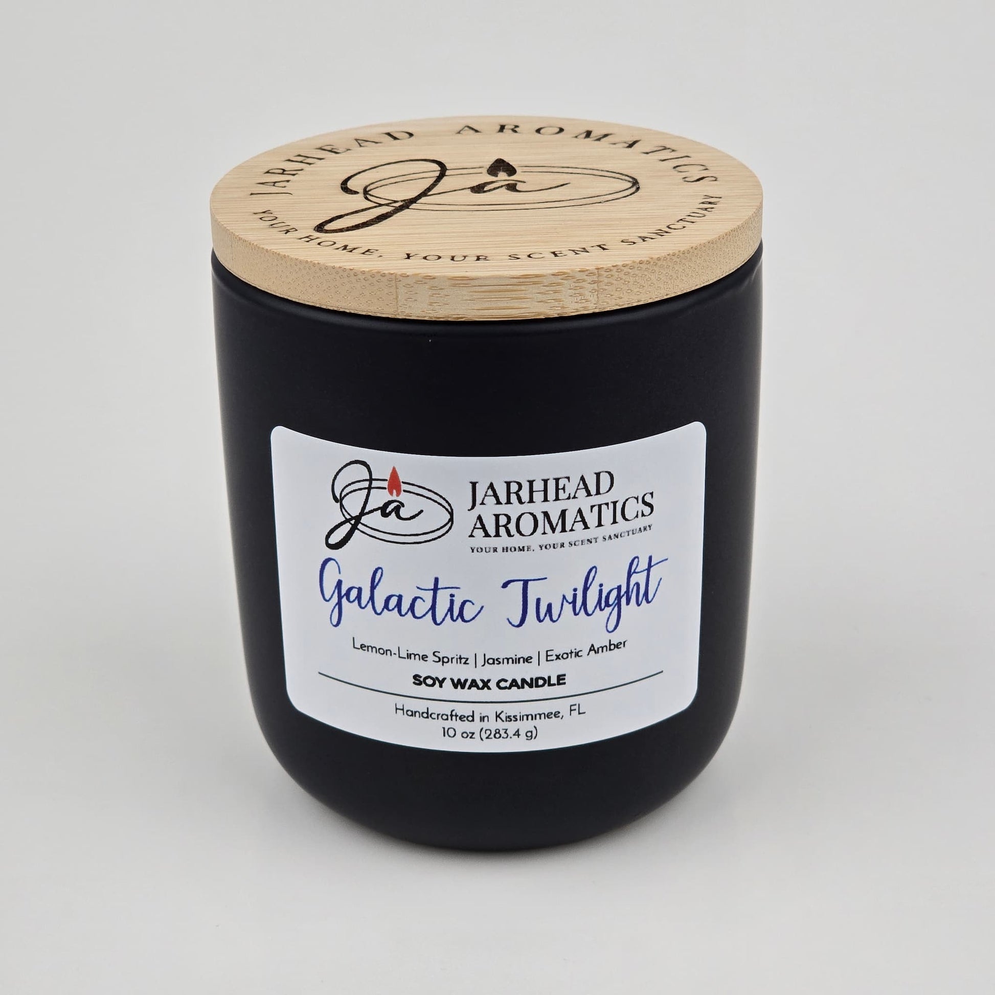A handcrafted black soy wax candle jar from Jarhead Aromatics, labeled Galactic Twilight Soy Wax Candle, features bergamot, jasmine, and amber scents. Made in Kissimmee, FL with a wooden lid.