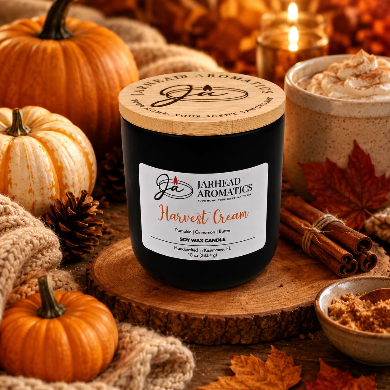 A Jarhead Aromatics Harvest Cream Soy Wax Candle—infused with notes of pumpkin spice, brown sugar, and vanilla—rests on a cozy table surrounded by pumpkins, pinecones, cinnamon sticks, a warm drink, and knit blankets, filling the air with an inviting fall fragrance and creating a festive autumn atmosphere.