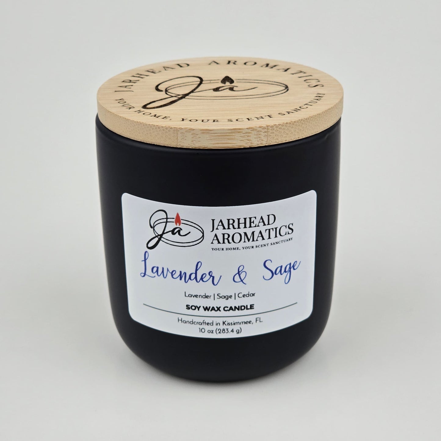 The Jarhead Aromatics Lavender & Sage Soy Wax Candle features calming notes of lavender, sage, and sandalwood. Hand-poured in Kissimmee, FL, this 10 oz candle comes in a black jar with a wooden lid—perfect for a soothing ambiance.
