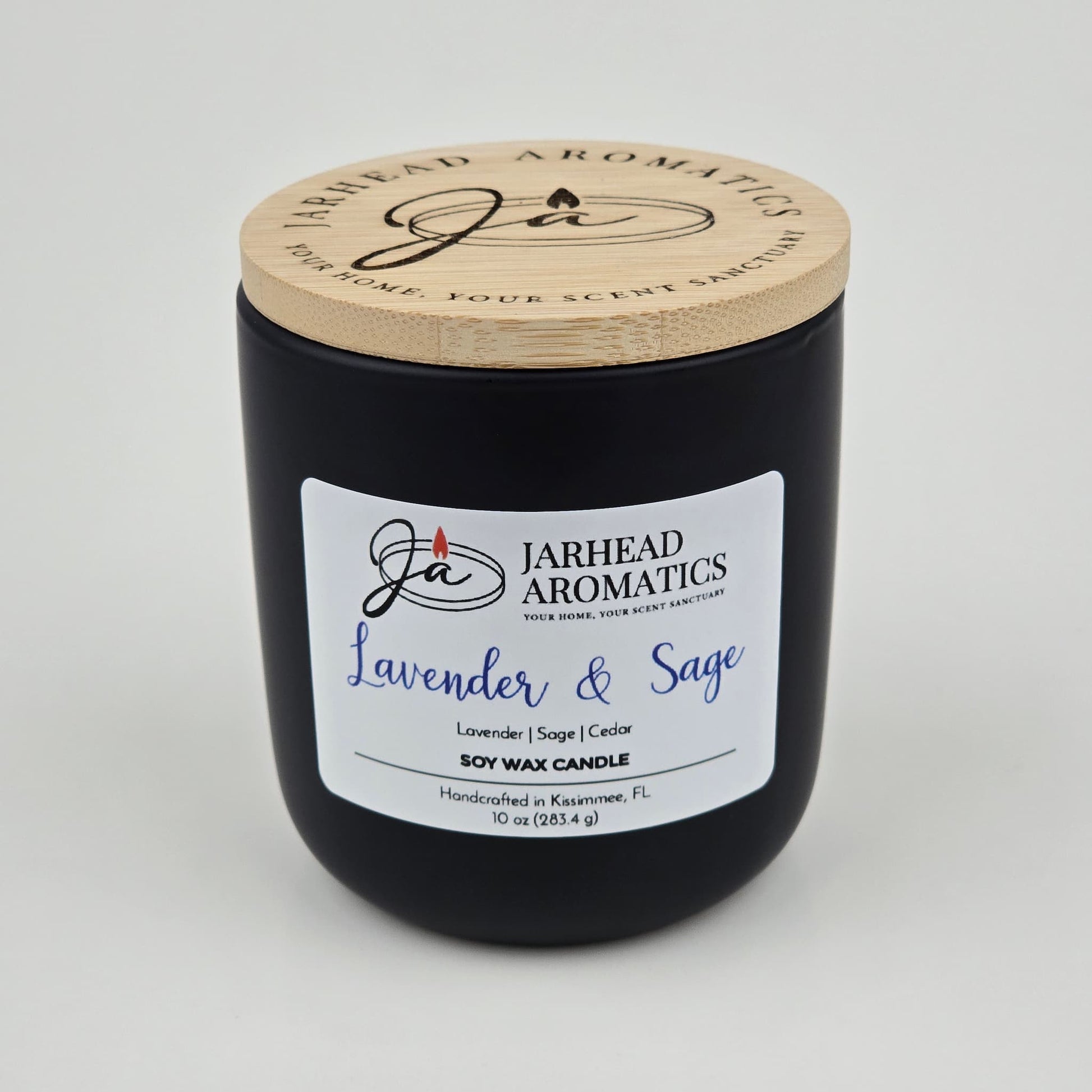 The Jarhead Aromatics Lavender & Sage Soy Wax Candle features calming notes of lavender, sage, and sandalwood. Hand-poured in Kissimmee, FL, this 10 oz candle comes in a black jar with a wooden lid—perfect for a soothing ambiance.