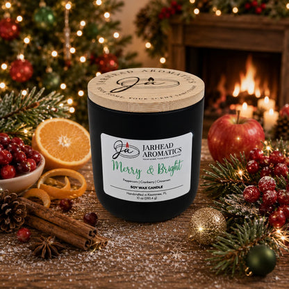 A Merry & Bright Soy Wax Candle by Jarhead Aromatics, with notes of citrus cranberry, warm spice, and fir, nestles among Christmas ornaments, fresh fruit, cinnamon sticks, and pine branches—infusing the space with a cozy holiday scent. In the background, a glowing fireplace and a decorated Christmas tree enhance this festive scene centered around the cheerful holiday candle.