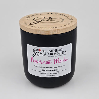 This Peppermint Mocha Soy Wax Candle by Jarhead Aromatics comes in a sleek black jar with a wooden lid. The white label describes scent notes of fresh mint, milk chocolate, and sweet peppermint, creating the perfect holiday ambiance. Featuring the comforting aroma of chocolate mint and vanilla, this 10 oz candle is an ideal choice for anyone who enjoys festive fragrances during the holiday season.