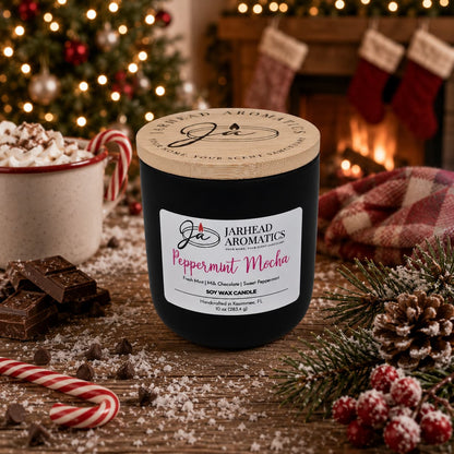 A Jarhead Aromatics Peppermint Mocha Soy Wax Candle | Chocolate Mint & Vanilla Holiday Candle sits on a holiday table surrounded by chocolate, candy canes, a cozy drink, a plaid cloth, and festive decorations. A fireplace with stockings hangs in the background, making this candle the perfect centerpiece for warm seasonal gatherings.