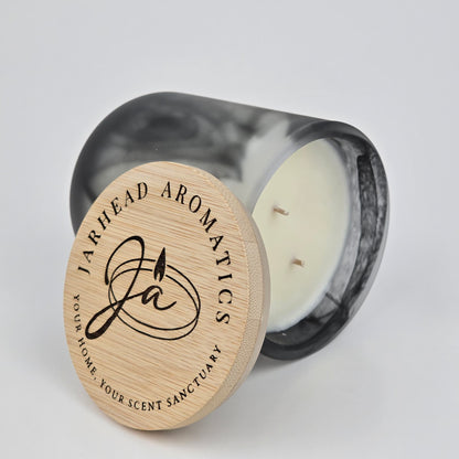 A marble-patterned candle jar lies on its side, topped with a wooden lid engraved with Jarhead Aromatics and the phrase "Your Home, Your Scent Sanctuary." Inside is the Zombie Queen Soy Wax Candle—a white, double-wicked candle that channels gothic allure through its Halloween-inspired fragrance of black tea, rose petals, and cedarwood.