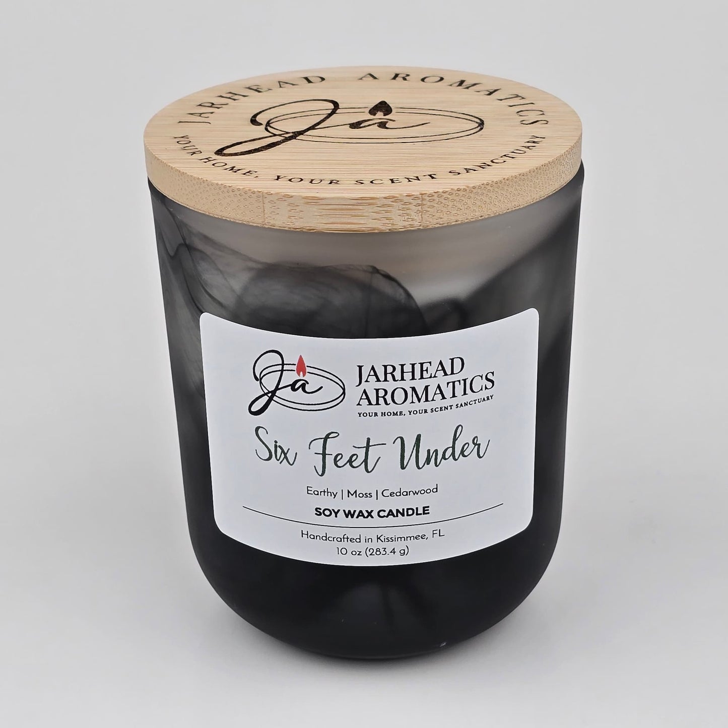Add an eerie vibe to your décor with the Six Feet Under Soy Wax Candle from Jarhead Aromatics. Housed in a sleek black jar with a wooden lid and crafted in Kissimmee, FL, this Halloween candle features notes of earthy moss, damp soil, and cedarwood—evoking the true essence of a cemetery.