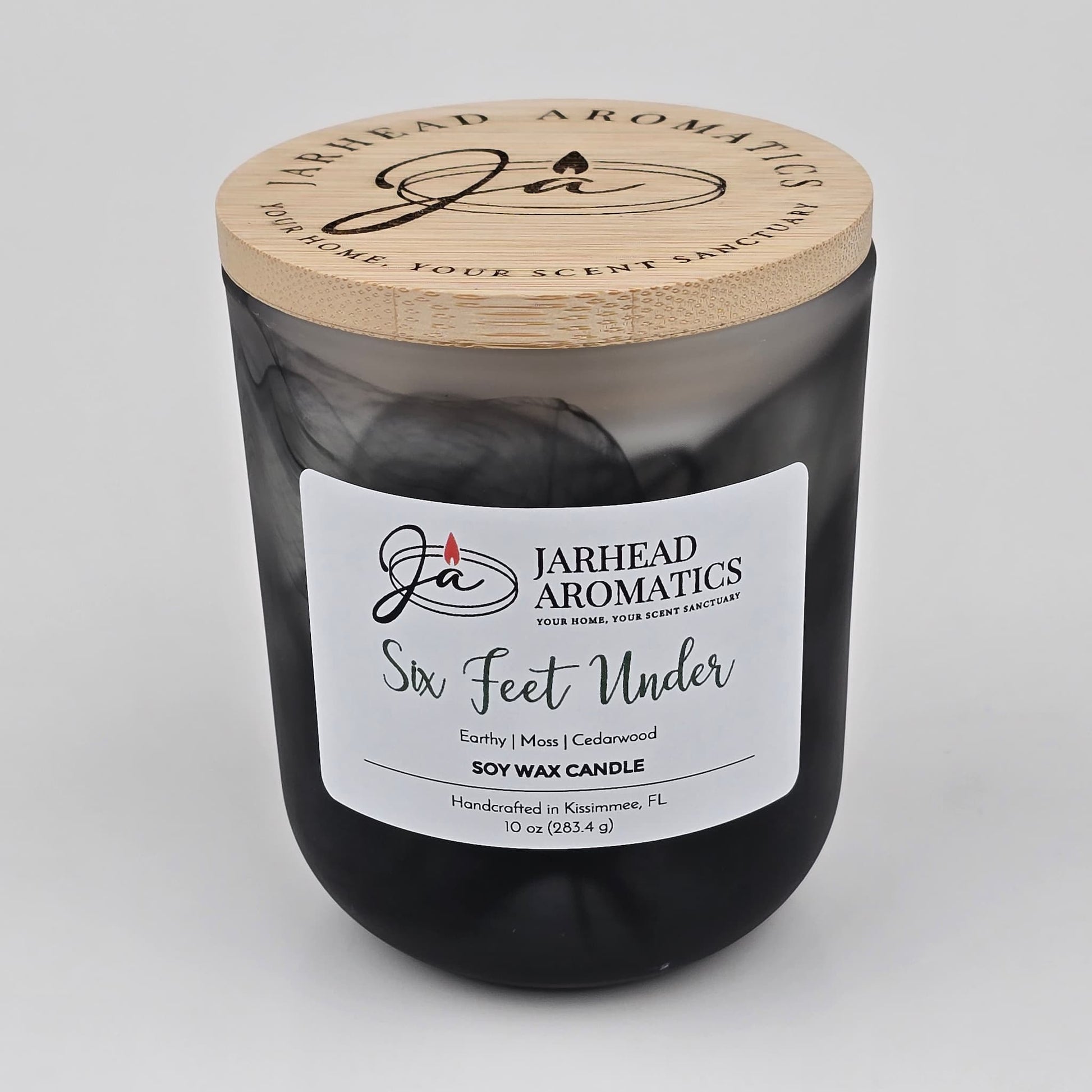 Add an eerie vibe to your décor with the Six Feet Under Soy Wax Candle from Jarhead Aromatics. Housed in a sleek black jar with a wooden lid and crafted in Kissimmee, FL, this Halloween candle features notes of earthy moss, damp soil, and cedarwood—evoking the true essence of a cemetery.