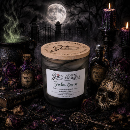 A Jarhead Aromatics Zombie Queen Soy Wax Candle—fragrant with black tea, rose petals, and cedarwood—glows amid gothic decor: a crowned skull, potion bottles, a Book of Shadows, and a steaming cauldron. The candle’s haunting Halloween aroma fills the air as moonlight casts eerie shadows on a graveyard tableau in the background.