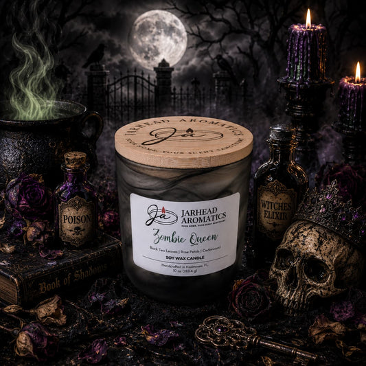 A Jarhead Aromatics Zombie Queen Soy Wax Candle—fragrant with black tea, rose petals, and cedarwood—glows amid gothic decor: a crowned skull, potion bottles, a Book of Shadows, and a steaming cauldron. The candle’s haunting Halloween aroma fills the air as moonlight casts eerie shadows on a graveyard tableau in the background.