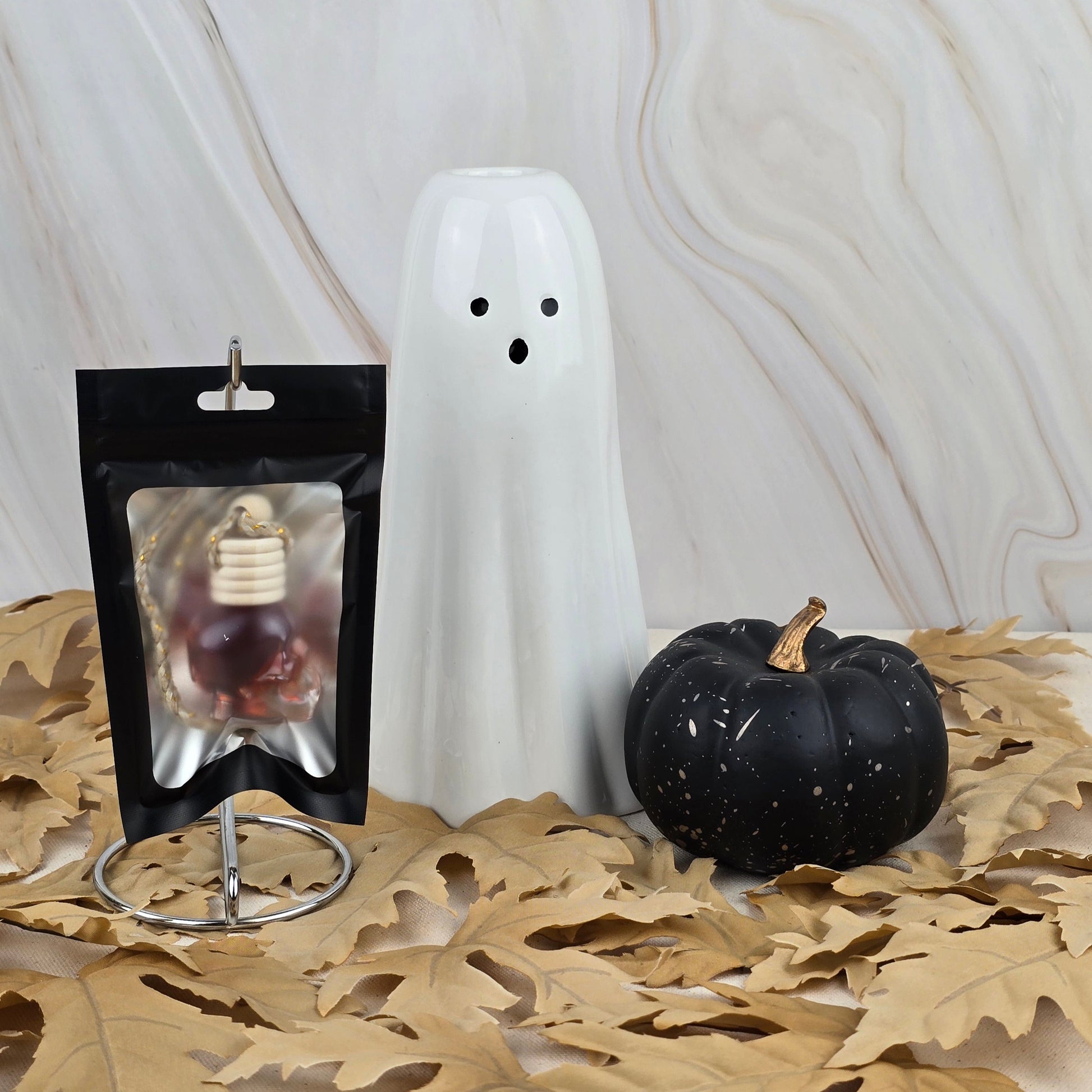 The Six Feet Under Car Diffuser from Jarhead Aromatics Halloween Collection rests on dried oak leaves with a marble background, suggesting a cemetery-inspired scent with woody undertones.
