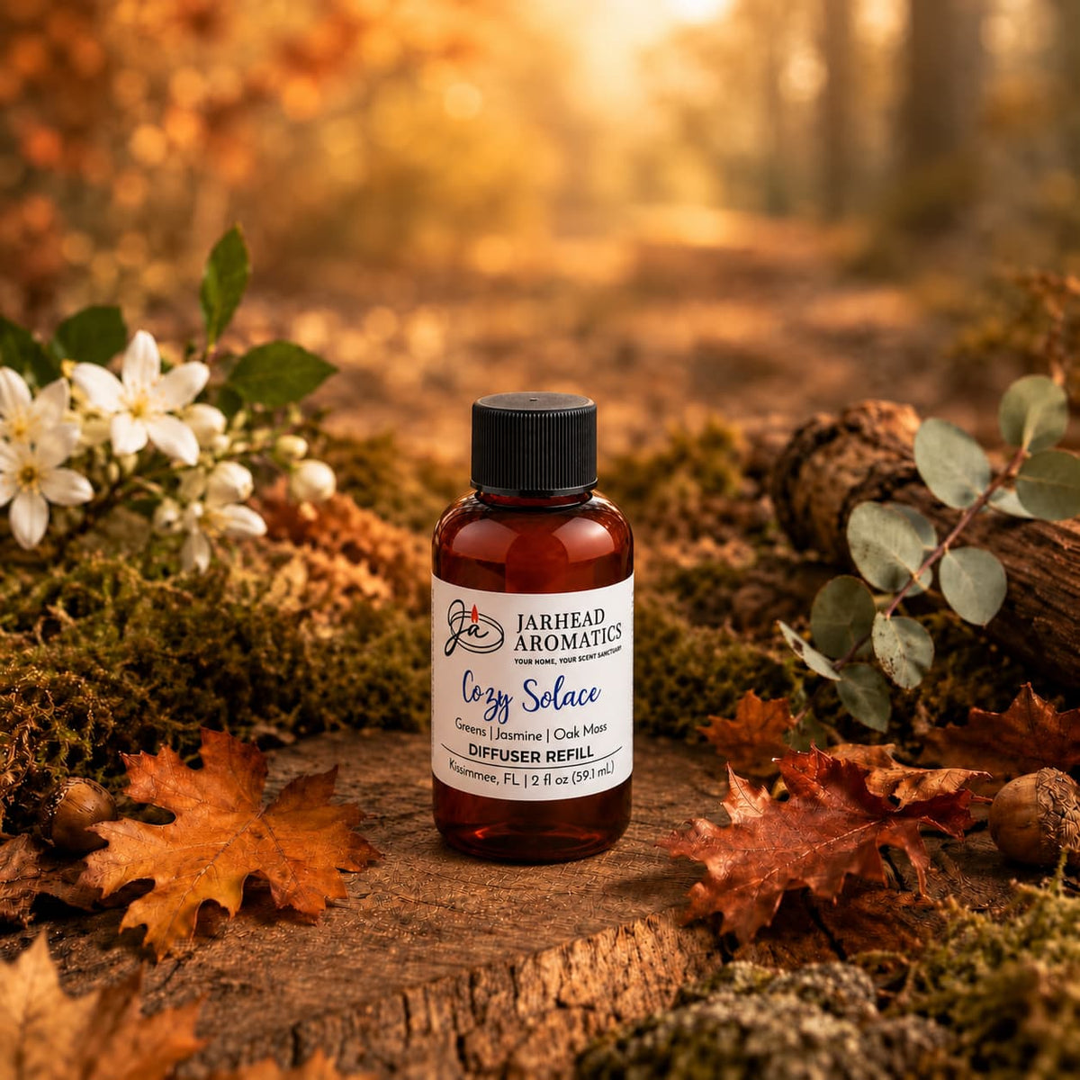 A bottle of Jarhead Aromatics’ Cozy Solace Diffuser Refill—featuring notes of fresh greens, jasmine, and oak moss—rests on a bed of moss in a sun-dappled autumn forest, surrounded by flowers, fallen leaves, and logs. The tranquil setting beautifully evokes the essence of this autumn-inspired home fragrance.