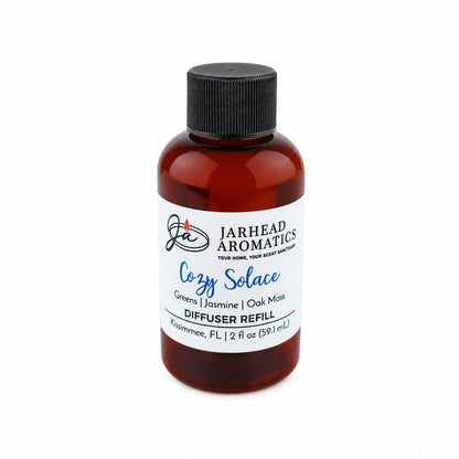 A brown bottle labeled Jarhead Aromatics Cozy Solace Diffuser Refill contains 2 fl oz (59.1 mL) of an autumn-inspired fragrance blend featuring fresh greens, jasmine, and oak moss notes. Complete with a black screw cap, this refill is perfect for use in your favorite home fragrance diffuser.