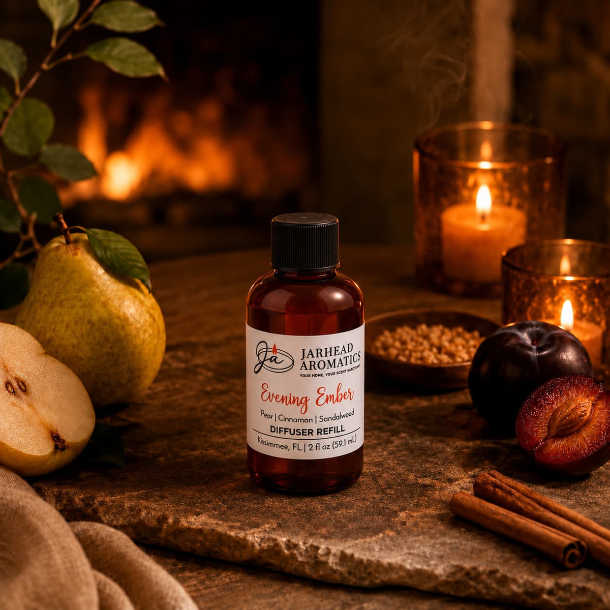 A bottle of Jarhead Aromatics Evening Ember Diffuser Refill | Plum, Sandalwood & Soft Smoke rests on a table surrounded by pears, plums, cinnamon sticks, and candles, with a fireplace in the background—setting the scene for a warm and cozy home fragrance atmosphere.