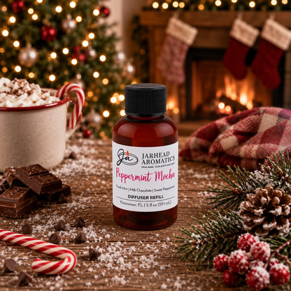 A bottle of Peppermint Mocha Diffuser Refill | Chocolate Mint & Vanilla by Jarhead Aromatics on a wooden table with chocolate, a candy cane, and a mug of hot cocoa, set against a Christmas tree and fireplace.