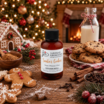 Amber glass bottle of Jarhead Aromatics Santa’s Cookies Diffuser Refill surrounded by gingerbread men, chocolate chip cookies, and cinnamon sticks on a wooden table in front of a Christmas tree.