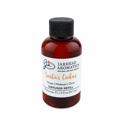 A small amber glass bottle of Jarhead Aromatics Santa’s Cookies Diffuser Refill with a black cap and a label detailing the scent notes of ginger, brown sugar, molasses, and vanilla.