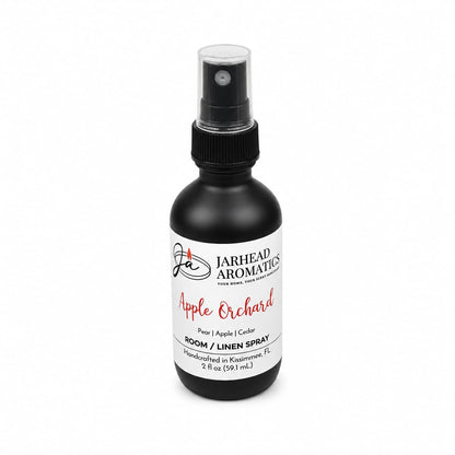 A 2 fl oz (59 mL) black spray bottle of Jarhead Aromatics’ Apple Orchard Room & Linen Spray | Crisp Apple, Pear & Cedarwood, this handcrafted home fragrance from Kissimmee, FL features notes of pear, apple, and cedarwood.