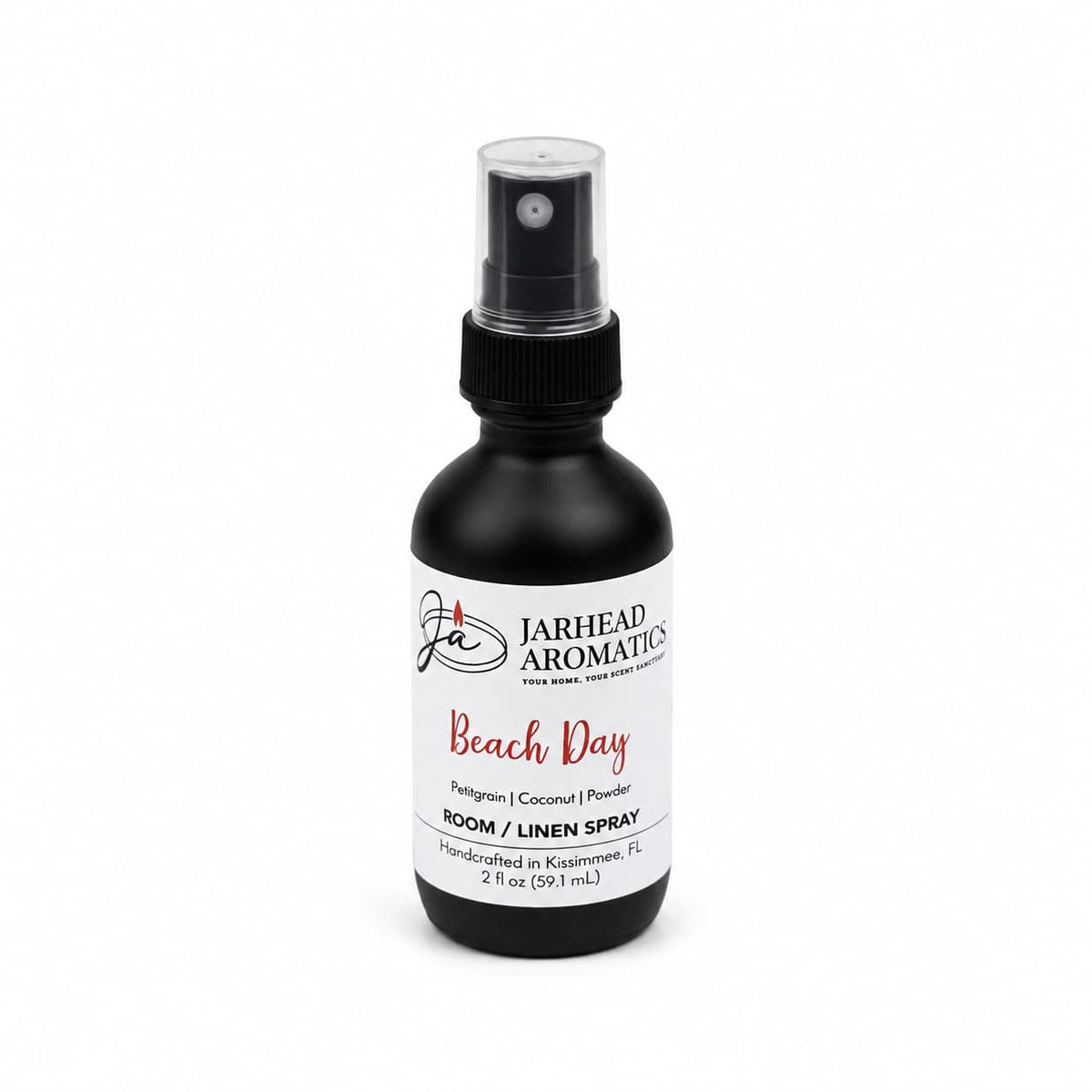 A sleek black spray bottle labeled Jarhead Aromatics Beach Day Room & Linen Spray | Citrus, Coconut & Coastal Musk features a blend of citrus, coconut, and coastal musk notes. Handcrafted in Kissimmee, FL, this 2 fl oz tropical room and linen spray infuses your home with the fresh essence of a beach-inspired fragrance for both linens and living spaces.