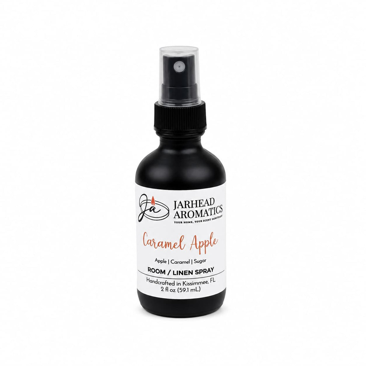 A black spray bottle labeled Jarhead Aromatics Caramel Apple Room & Linen Spray features notes of crisp apple, caramel, and warm spice. The label highlights that the product is handcrafted in Kissimmee, FL. This Caramel Apple Room & Linen Spray is perfect for filling your home with a cozy fall fragrance or refreshing your linens with a sweet autumn scent.