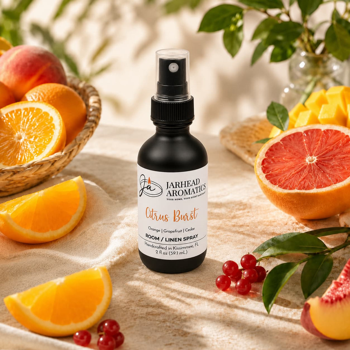 A bottle of Jarhead Aromatics Citrus Burst Room & Linen Spray | Orange, Mango, Grapefruit & Peach rests on a table amid fresh oranges, mangoes, grapefruits, and peaches, accented by green leaves and sunlight—a vibrant home fragrance that infuses your space with the lively scent of tropical fruits.