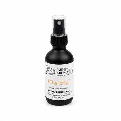 A black spray bottle labeled Jarhead Aromatics Citrus Burst Room & Linen Spray, featuring a refreshing blend of orange, mango, grapefruit, and peach for a vibrant home fragrance experience. The 2 oz bottle sports a white label with bold black and orange text, perfect for those who love an uplifting tropical fruit scent.