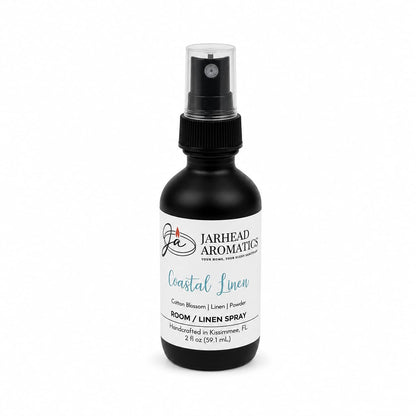 A black spray bottle labeled Jarhead Aromatics Coastal Linen Room & Linen Spray, featuring fresh linen, ozone, and sandalwood scents. This handcrafted room and linen spray delivers a refreshing home fragrance experience with every spritz. The 2 fl oz bottle is carefully made in Kissimmee, FL.