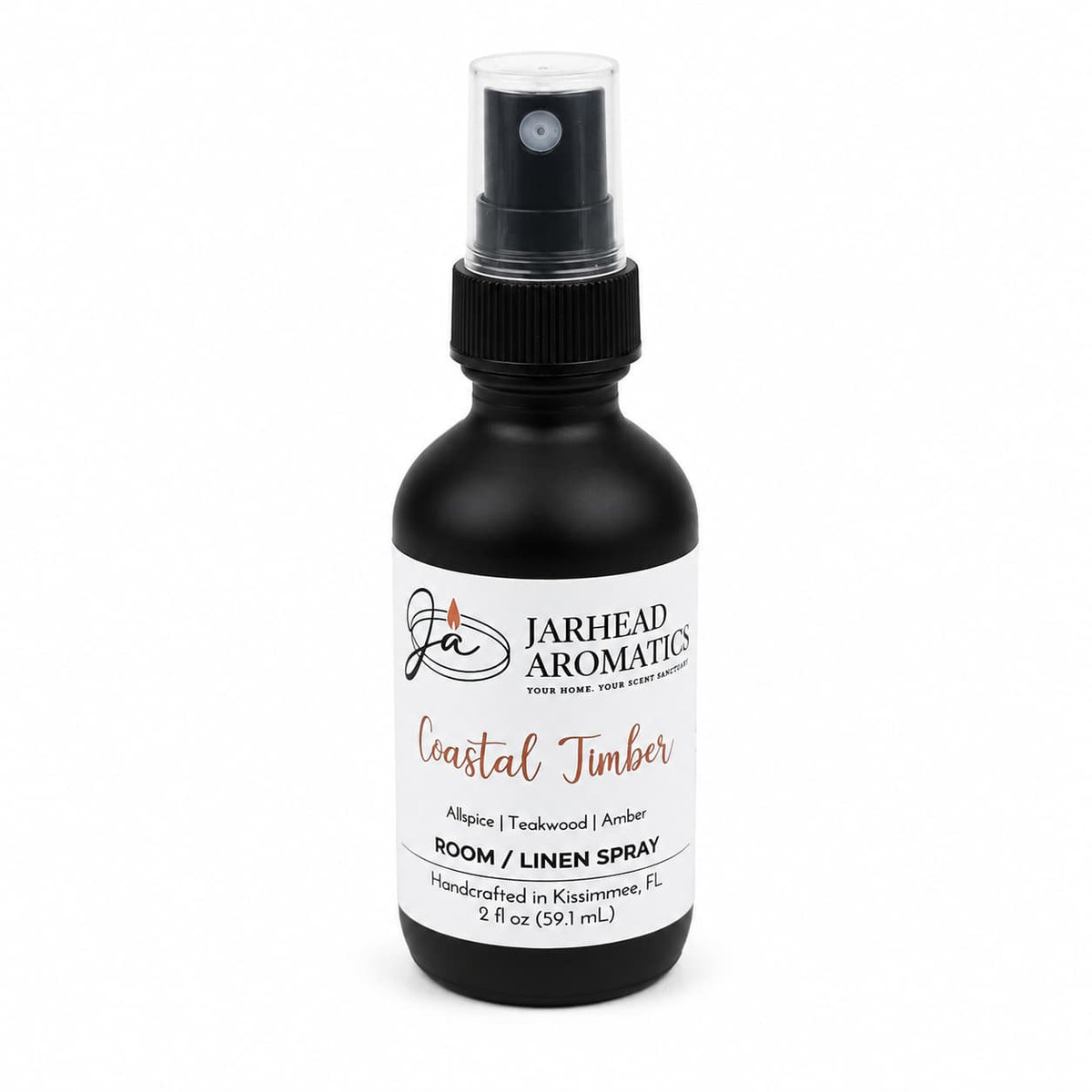 A black 2 fl oz spray bottle from Jarhead Aromatics, this Coastal Timber Room & Linen Spray features a white label with black and orange text. Enjoy a luxurious woodsy home fragrance with notes of teakwood, leather, and warm amber.