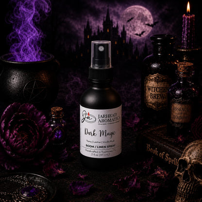 A bottle of Jarhead Aromatics Dark Magic Room & Linen Spray | Peach, Plum, Dark Florals & Vanilla Musk rests on a table encircled by purple flowers, potion bottles, and a spellbook, with wisps of smoke swirling beneath a full moon and flying bats—evoking an enchanting and mystical home fragrance scene.