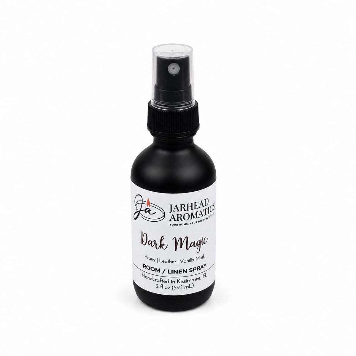 A black spray bottle labeled Jarhead Aromatics Dark Magic Room & Linen Spray is displayed on a white background, featuring an enchanting home fragrance with notes of peach, plum, dark florals, and vanilla musk; 2 oz (59 ml), handcrafted in Kissimmee, FL.