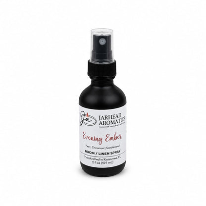 A black spray bottle labeled Jarhead Aromatics Evening Ember Room & Linen Spray, featuring a home fragrance profile with notes of plum, sandalwood, and soft smoke, 2 oz, set against a white background.