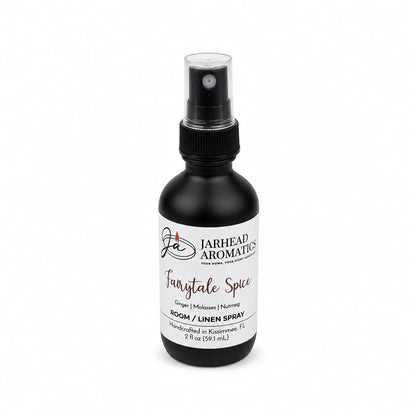 A black spray bottle labeled “Jarhead Aromatics Fairytale Spice Room & Linen Spray | Gingerbread, Molasses & Warm Spice” offers a bakery-inspired home fragrance with notes of gingerbread, molasses, and warm spices, reminiscent of a gingerbread house. The bottle contains 2 fl oz (59 mL).