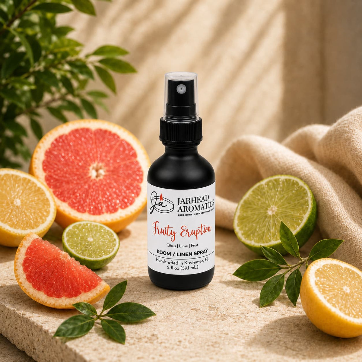 A bottle of Jarhead Aromatics Fruity Eruption Room & Linen Spray | Lemon, Lime, Grapefruit & Fresh Fruit sits on a beige surface, surrounded by sliced grapefruit, lemon, lime, and orange, with green leaves and a beige cloth in the background. Infused with a vibrant blend of citrus notes and fresh fruit, this room spray instantly revitalizes your space—making it an ideal addition to your home fragrance collection.