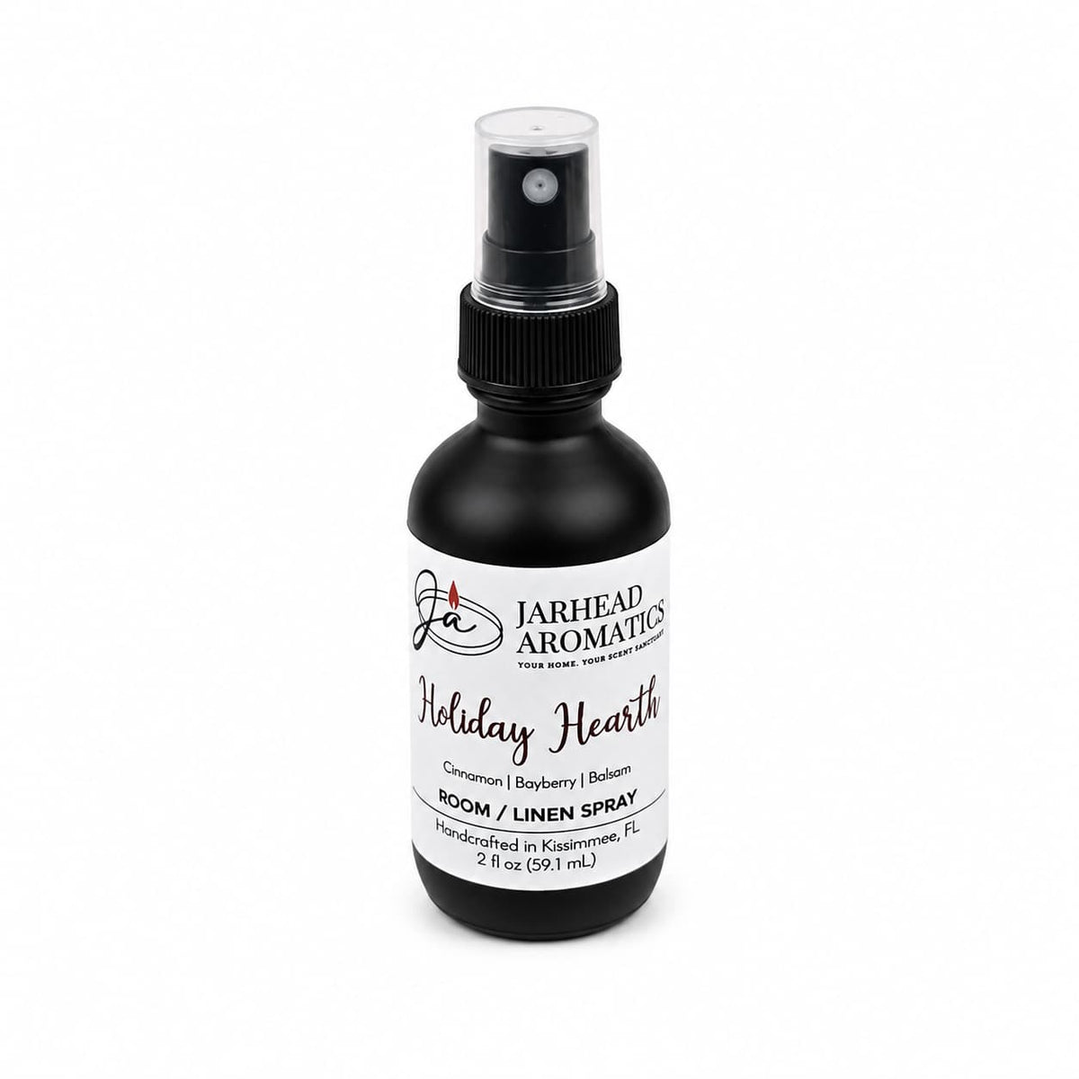 A black Jarhead Aromatics Holiday Hearth Room & Linen Spray bottle with a white label listing the scents cinnamon, clove, bayberry, and balsam.