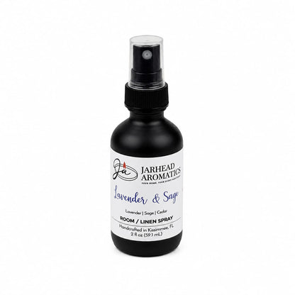 A black spray bottle labeled Jarhead Aromatics Lavender & Sage Room & Linen Spray (Lavender, Sage & Sandalwood) is displayed against a white background, providing a calming fragrance ideal for use as both a room and linen spray.