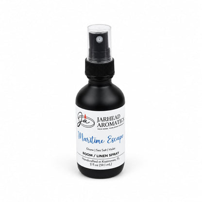 A 2 fl oz black spray bottle of Jarhead Aromatics Maritime Escape Room & Linen Spray | Sea Salt, Ozone & Jasmine is shown with blue and white accents on a white background. This home fragrance captures a refreshing coastal aroma crafted to evoke the calm of the sea in any room or linen closet.