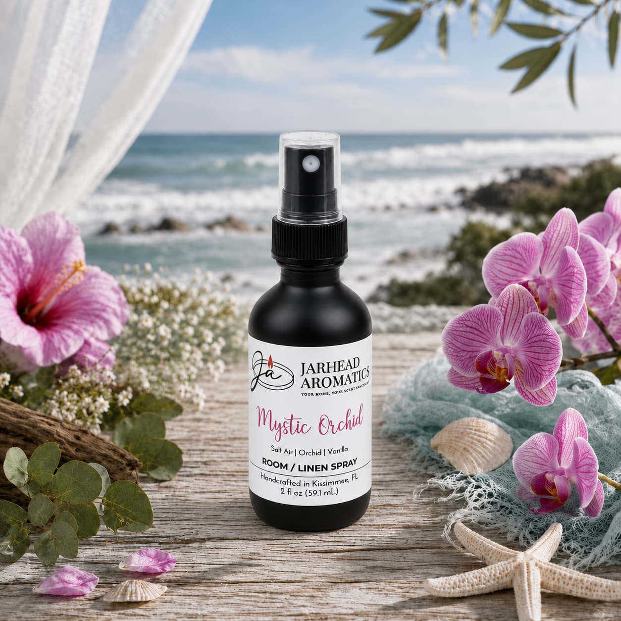 A bottle of Mystic Orchid Room & Linen Spray by Jarhead Aromatics rests on a table decorated with pink orchids and lush greenery, releasing notes of orchid, salt air, and vanilla into the air, while a tranquil beach with rolling ocean waves sets the serene backdrop—creating an inviting home fragrance ambiance.