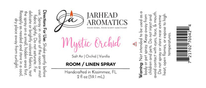 White label for Jarhead Aromatics Mystic Orchid Room & Linen Spray | Orchid, Salt Air & Vanilla. This coastal floral fragrance fills your space with a captivating combination of orchid, creamy vanilla, and fresh salt air for a revitalizing home fragrance experience. Features directions, ingredients, warnings, and product details in black and pink text. Logo showcases an orange flame above the Jarhead Aromatics brand name. Expertly crafted as the Mystic Orchid Room & Linen Spray to refresh any room or linen.